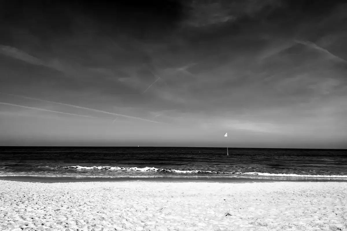 Strand und Brandung unter hellem Himmel, schwarz-weiß – Foto: Jan Pleitner